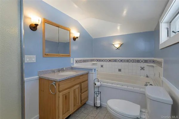 a bathroom with a granite countertop toilet sink and mirror