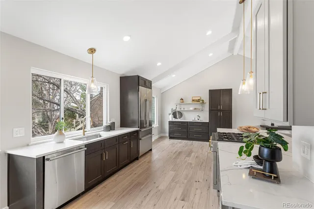 a large white kitchen with a large window a sink and stainless steel appliances