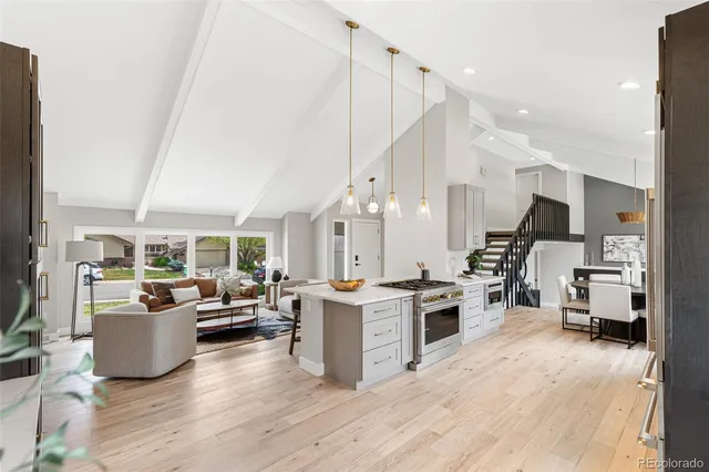 a open kitchen with stainless steel appliances kitchen island granite countertop a stove top oven a sink a dining table and chairs with wooden floor