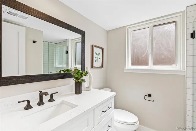 a bathroom with a sink vanity granite toilet and a mirror