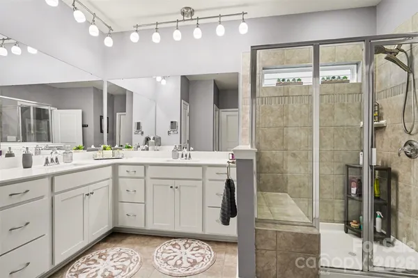 a spacious bathroom with a shower a sink and a mirror