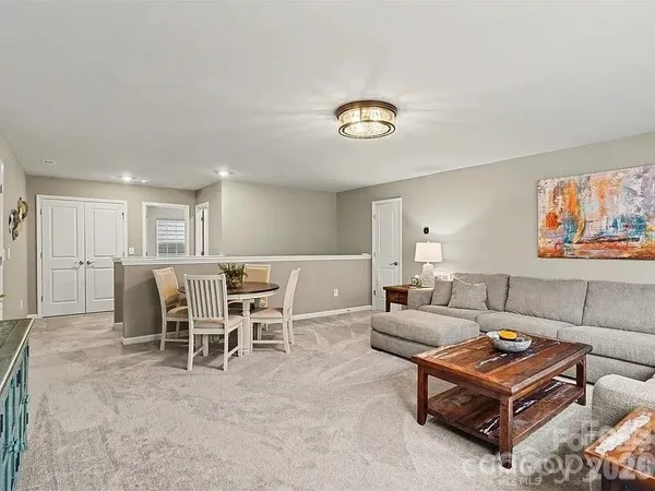 a living room with furniture a table and kitchen view