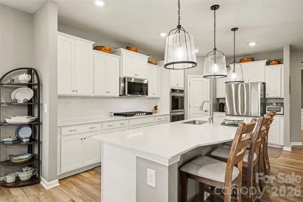 a kitchen with stainless steel appliances kitchen island granite countertop a table chairs and a refrigerator