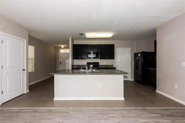 a view of kitchen with stainless steel appliances kitchen island sink and refrigerator