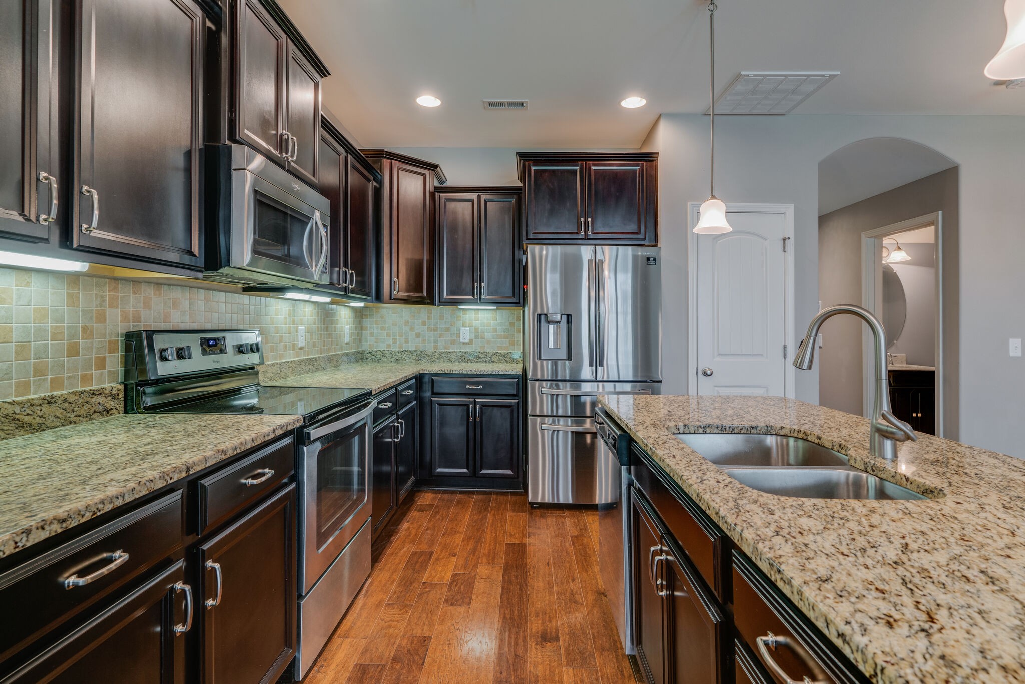 a kitchen with stainless steel appliances granite countertop a sink a stove top oven a refrigerator and dishwasher