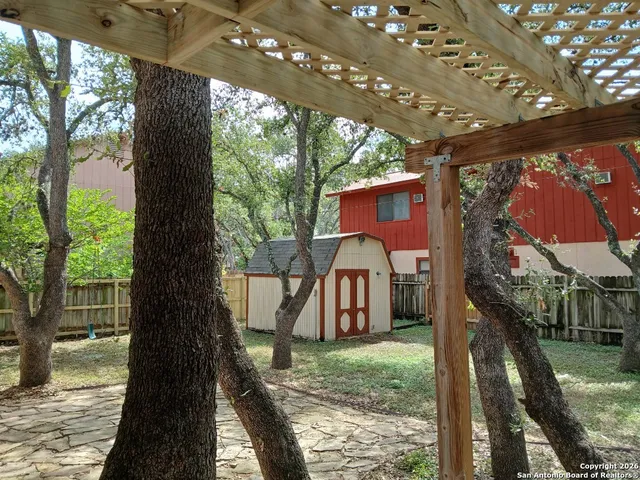 a view of a yard in front of a house with a large tree