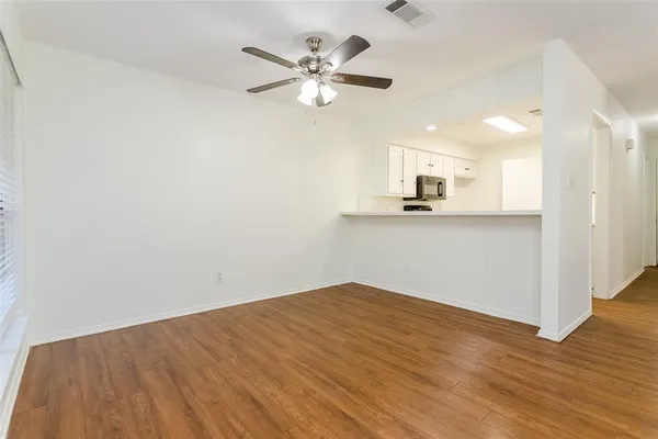 a view of a kitchen with wooden floor and a ceiling fan