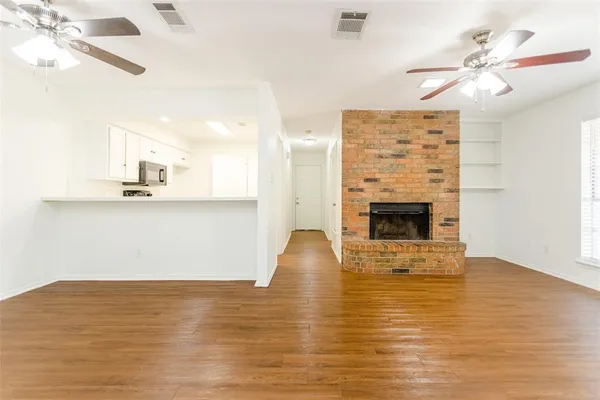 a view of kitchen and empty room with wooden floor