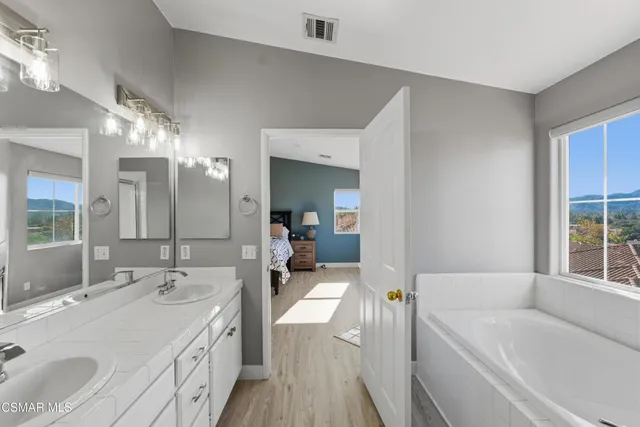 a en suite bathroom with a granite countertop tub sink and mirror