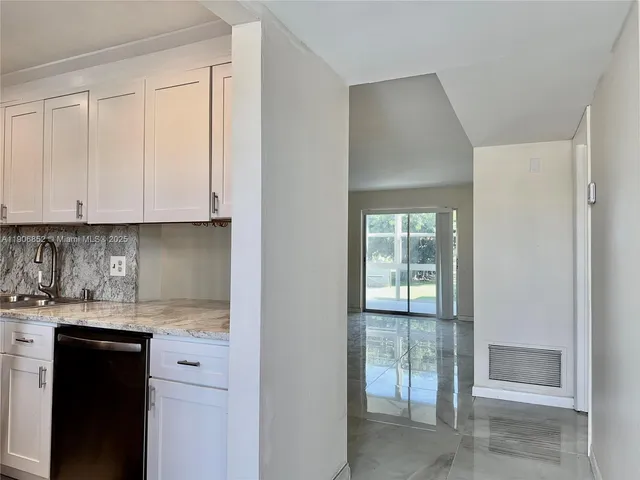a kitchen with granite countertop white cabinets and sink