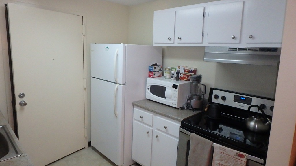 6 Post Oak Lane, Unit 4 Natick, MA 01760 - Photo 3 of 18 a kitchen with a refrigerator and white cabinets