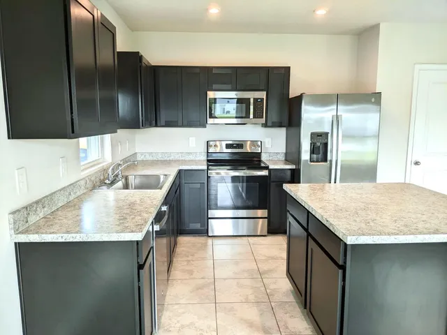 a kitchen with stainless steel appliances granite countertop a sink stove and refrigerator