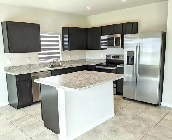 a kitchen with stainless steel appliances granite countertop a stove a refrigerator and a sink