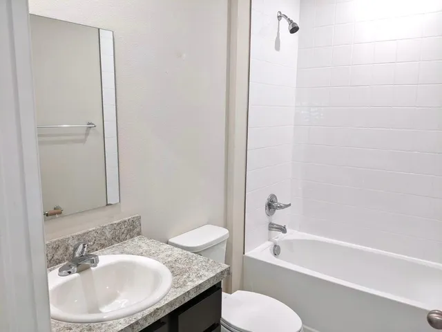 a bathroom with a granite countertop sink toilet and shower