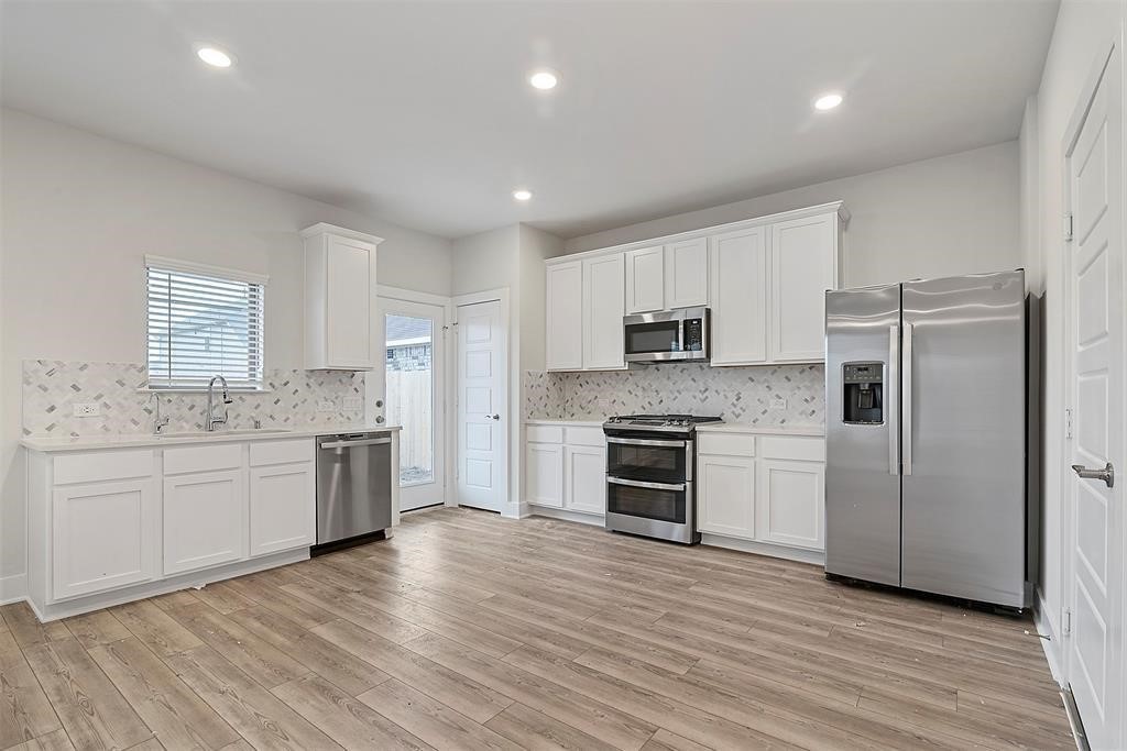 10638 Whitejacket Conroe, TX 77385 - Photo 3 of 25 a large kitchen with cabinets wooden floor and stainless steel appliances
