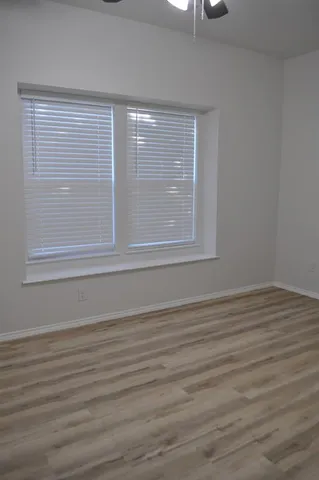 a view of an empty room with wooden floor and a chandelier fan