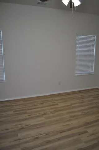 a view of an empty room with wooden floor and a window