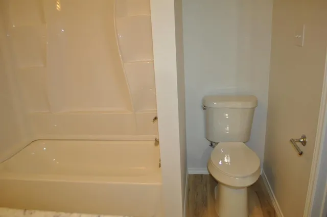 a view of an empty room with wooden floor and closet