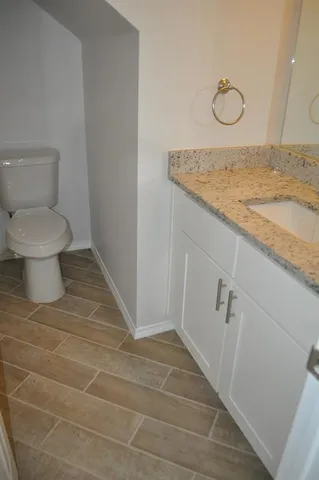 a bathroom with a granite countertop sink and a toilet