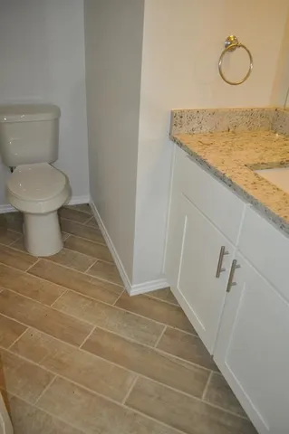 a bathroom with a granite countertop toilet and a sink