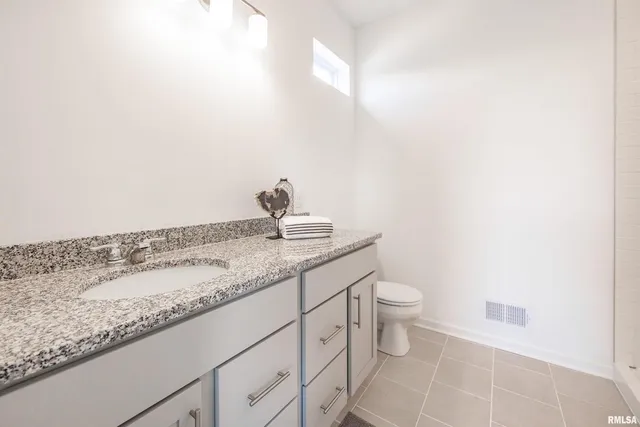 a bathroom with a granite countertop sink and a toilet