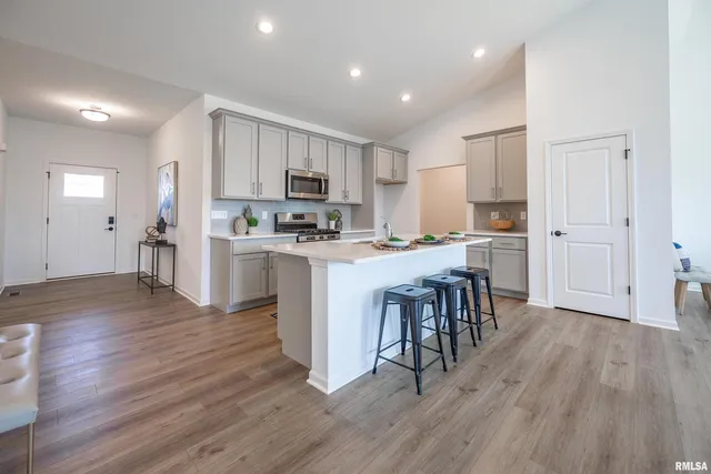 a kitchen with stainless steel appliances a dining table chairs microwave and cabinets