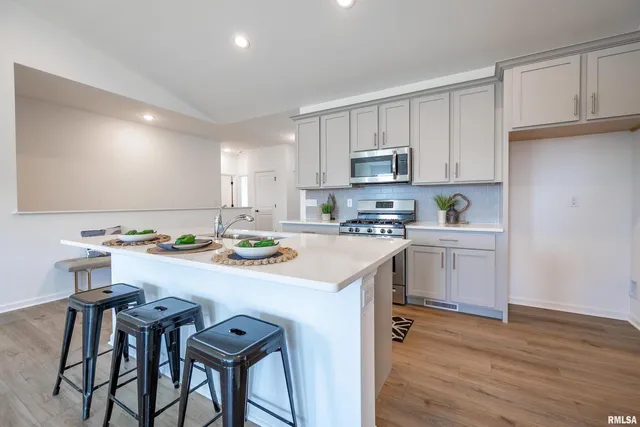 a kitchen with a sink a stove cabinets dining table and chairs