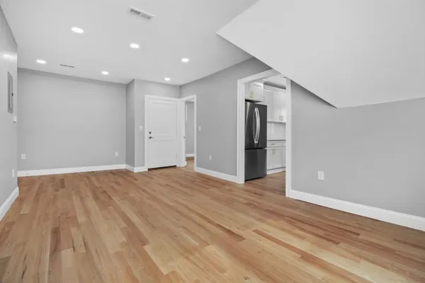 a view of an empty room with wooden floor and closet
