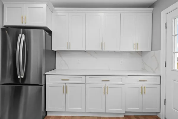 a kitchen with white cabinets and refrigerator