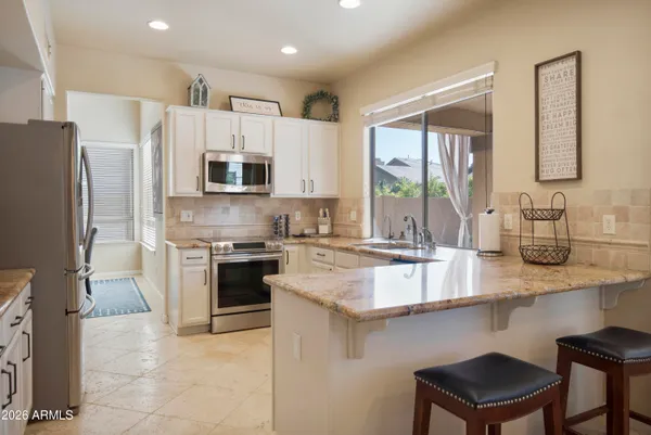 a kitchen with stainless steel appliances granite countertop a refrigerator sink and white cabinets