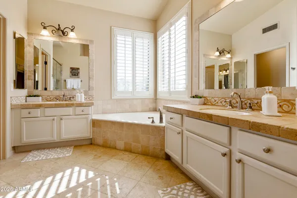 a bathroom with a granite countertop tub sink and mirror