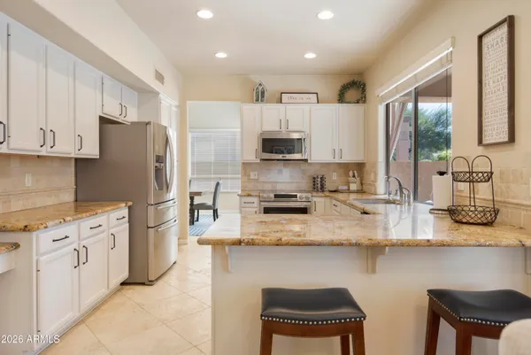 a kitchen with stainless steel appliances granite countertop a stove top oven a refrigerator a sink and white cabinets