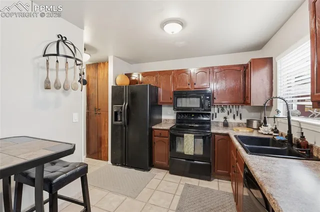 a kitchen with stainless steel appliances a sink a stove a refrigerator cabinets and a dining table