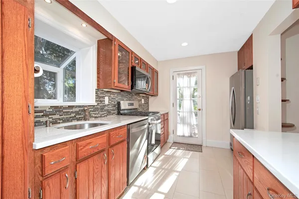 a large kitchen with stainless steel appliances granite countertop a refrigerator a sink dishwasher a stove and white countertops with wooden floor