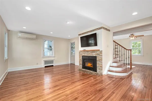 a view of an empty room with wooden floor fireplace and a window
