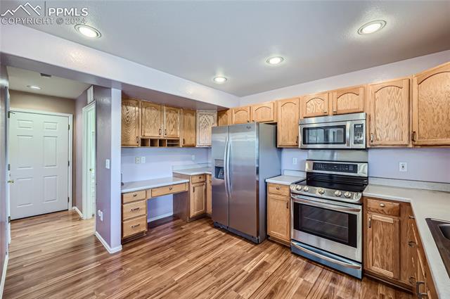 12510 Motley Road Peyton, CO 80831 - Photo 14 of 36 Kitchen featuring appliances with stainless steel finishes, built in desk, and wood-type flooring