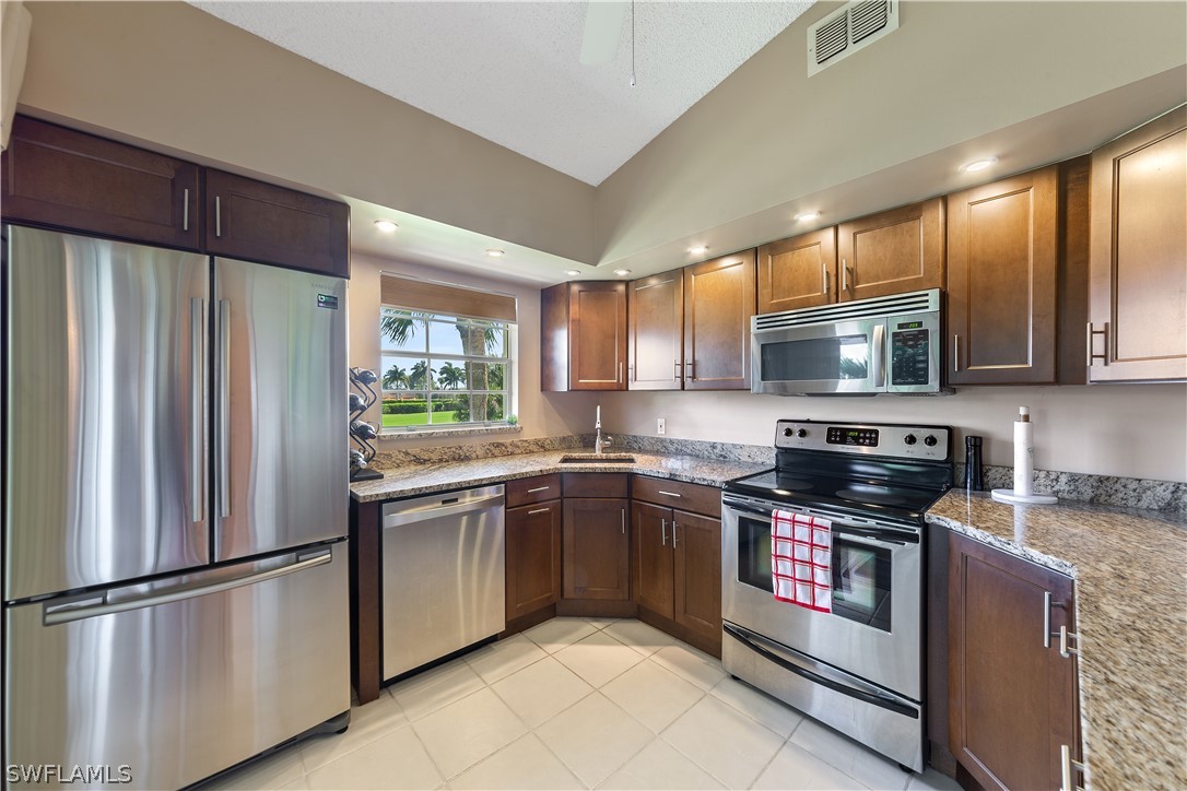 a kitchen with stainless steel appliances granite countertop a refrigerator stove microwave and sink
