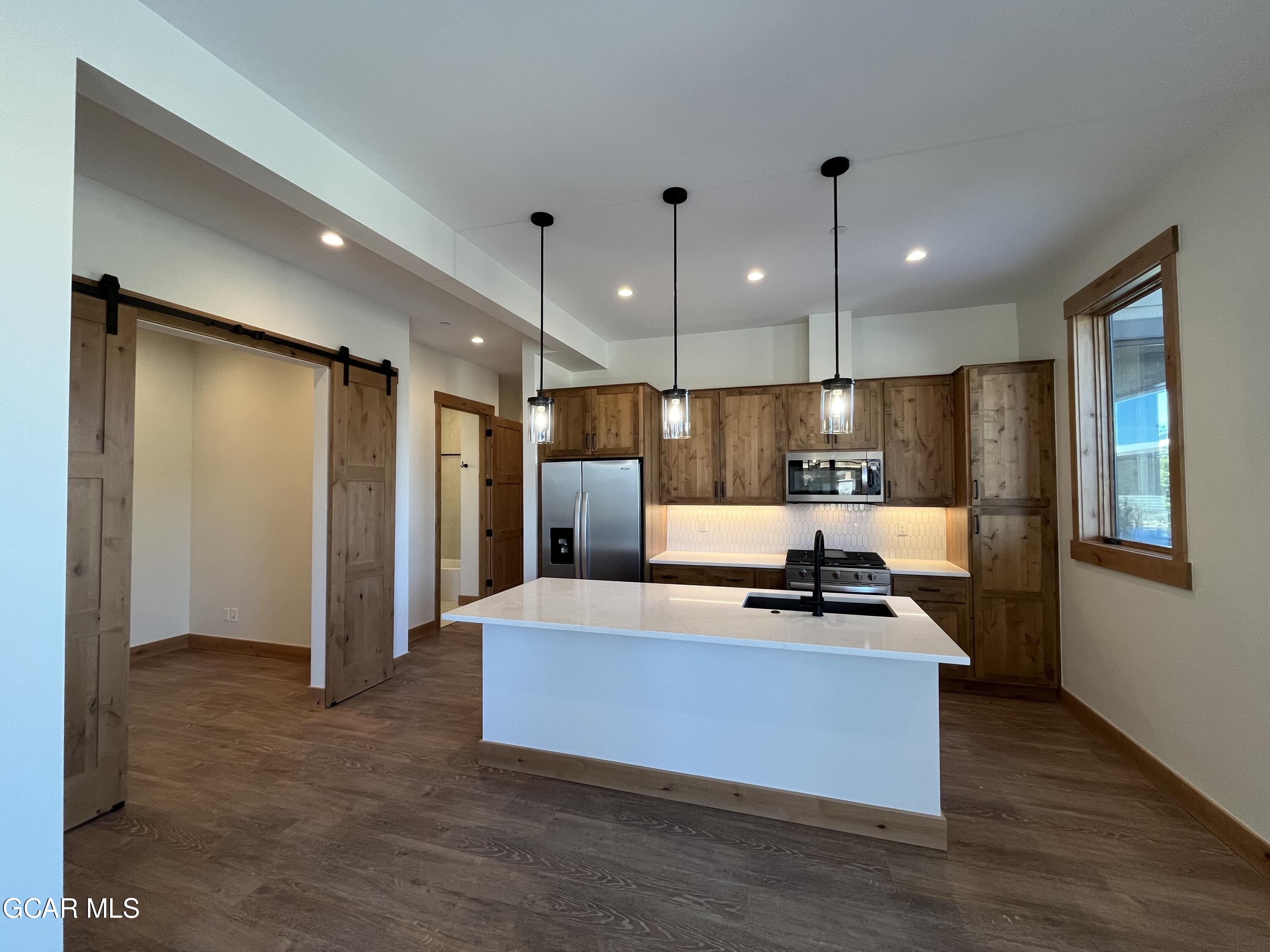 a large kitchen with kitchen island a counter top space a sink stainless steel appliances and cabinets