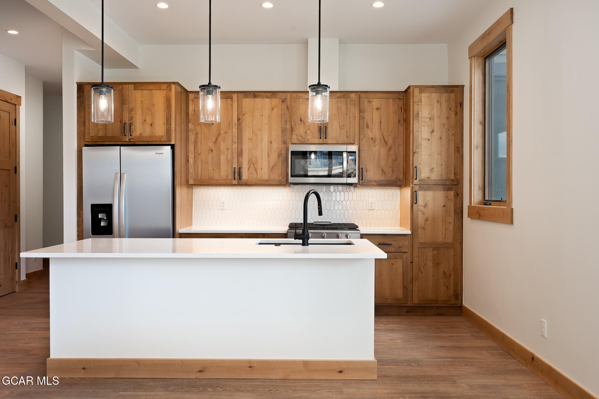 a kitchen with stainless steel appliances a refrigerator a sink a stove a microwave and wooden floor