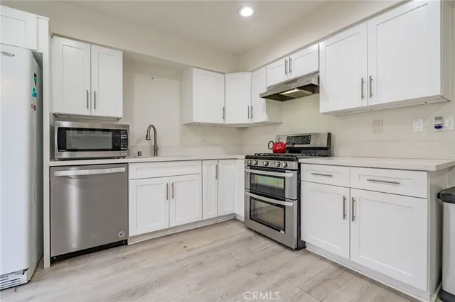 a kitchen with white cabinets stainless steel appliances and sink