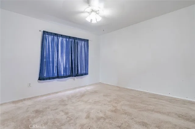an empty room with a fireplace and chandelier fan