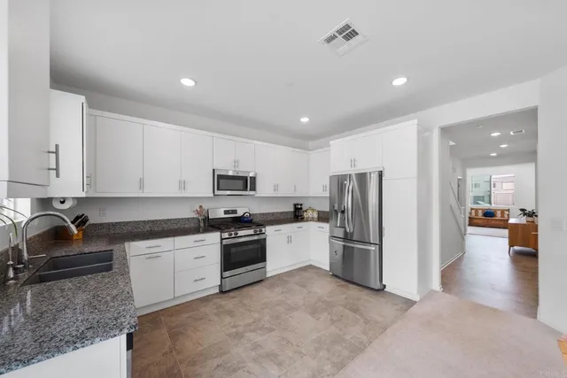 a kitchen with stainless steel appliances kitchen island granite countertop a refrigerator and a dining table
