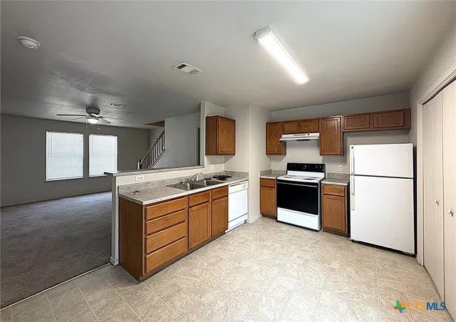 a large kitchen with stainless steel appliances granite countertop a stove a sink and a refrigerator