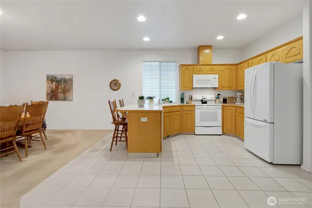 a kitchen with stainless steel appliances a refrigerator a sink a stove top oven and a dining table with wooden floor