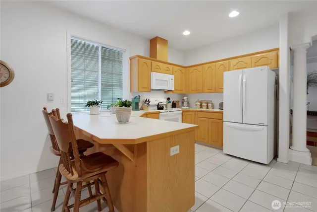 a kitchen with a refrigerator a stove a sink and a dining table with wooden cabinet