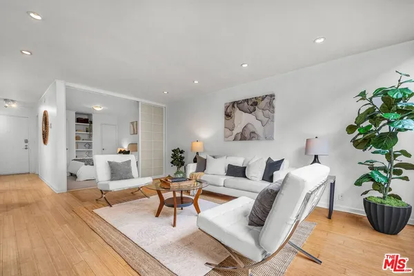 a living room with furniture potted plant and kitchen view