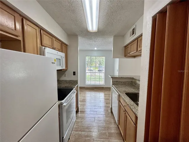 a kitchen with granite countertop a stove and a refrigerator