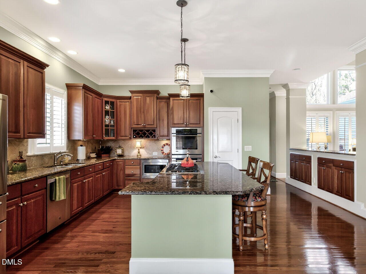 8409 Passage Marseille Court Raleigh, NC 27615 - Photo 9 of 48 a kitchen with kitchen island granite countertop a stove top oven a sink dishwasher a dining table and chairs with wooden floor