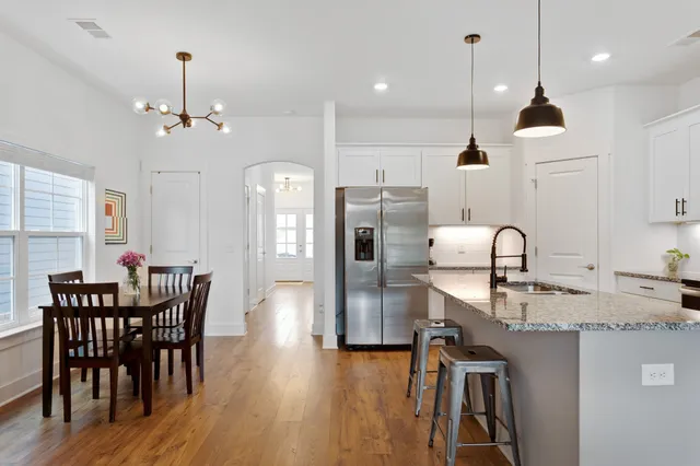 a kitchen with stainless steel appliances granite countertop a kitchen island hardwood floor a dining table and chairs