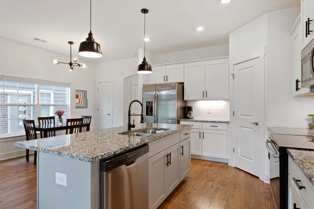 a kitchen with kitchen island granite countertop a sink a center island a stove and a dining table